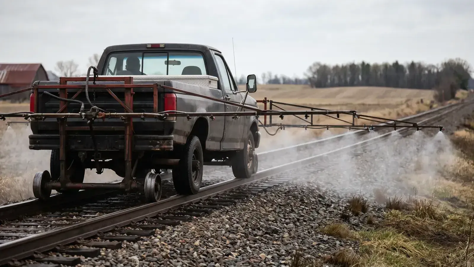 A hi-rail truck spraying herbicide along railroad track
