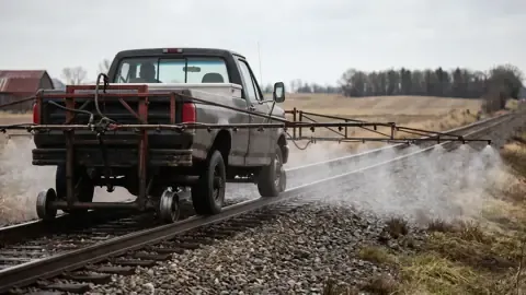 A hi-rail truck spraying herbicide along railroad track