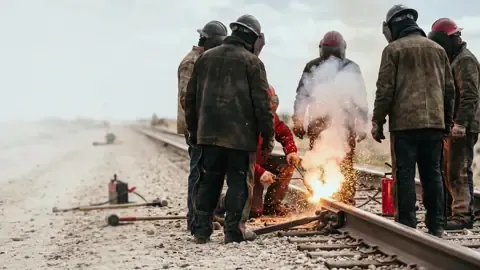 Sparks and welding fumes from a rail weld on the track